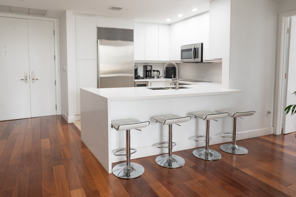 Photo of a small modern u-shaped eat-in kitchen in Miami with white cabinets.