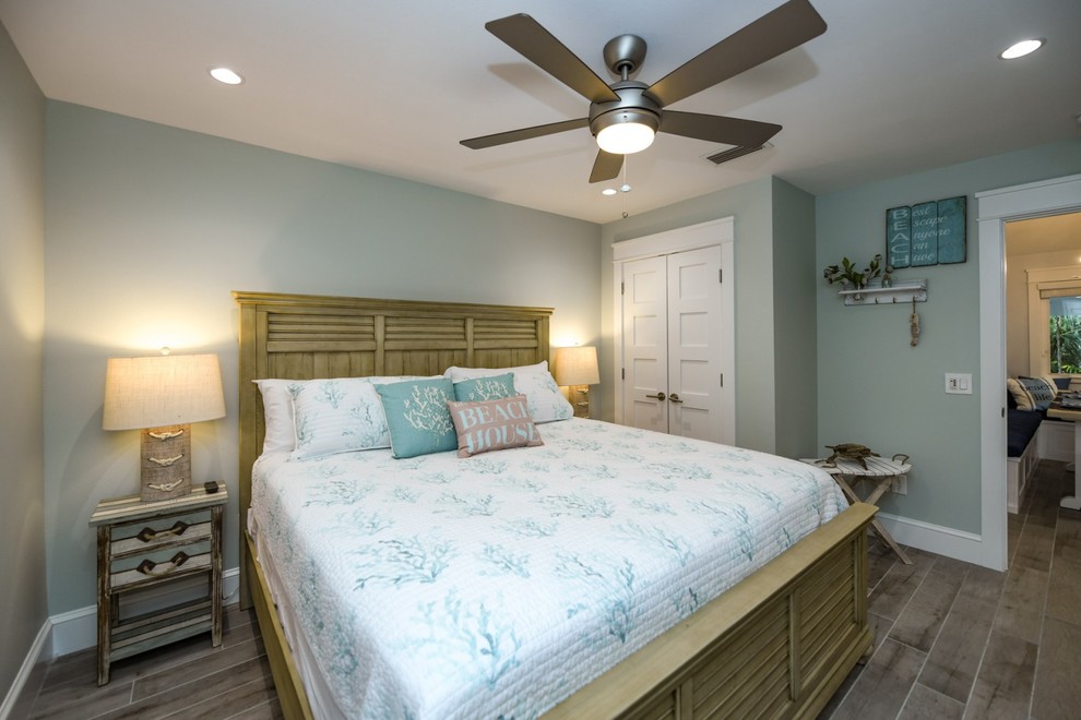 This is an example of a beach style guest bedroom in Tampa with green walls, porcelain floors and grey floor.