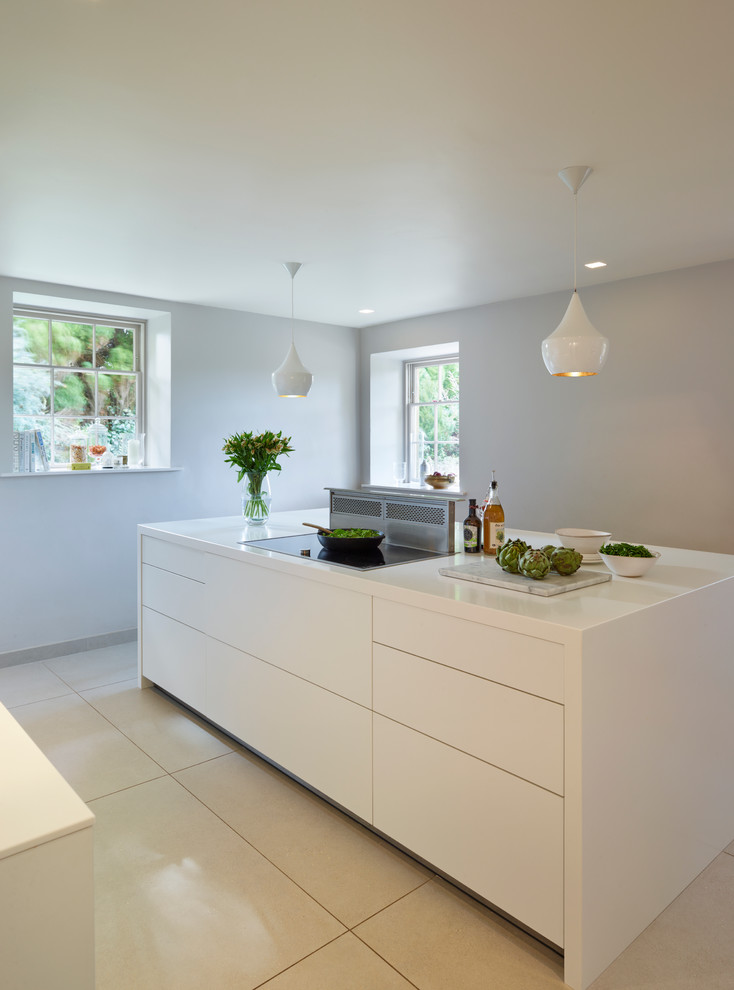 This is an example of a modern eat-in kitchen in Wiltshire with an integrated sink, flat-panel cabinets, white cabinets, white splashback, glass sheet splashback, stainless steel appliances, porcelain floors and with island.