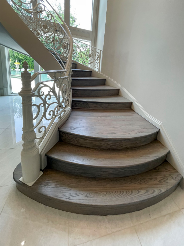 Ejemplo de escalera suspendida clásica renovada extra grande con escalones de madera, contrahuellas de madera, barandilla de metal y panelado