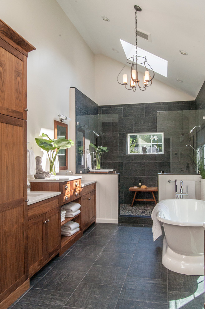 Design ideas for a modern master bathroom in Philadelphia with an undermount sink, medium wood cabinets, a freestanding tub, a two-piece toilet, black tile, porcelain tile, beige walls, pebble tile floors, engineered quartz benchtops, an open shower and shaker cabinets.