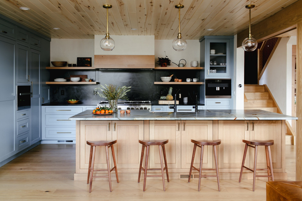 Exempel på ett stort rustikt grå grått kök, med skåp i shakerstil, blå skåp, svart stänkskydd, integrerade vitvaror, ljust trägolv och en köksö
