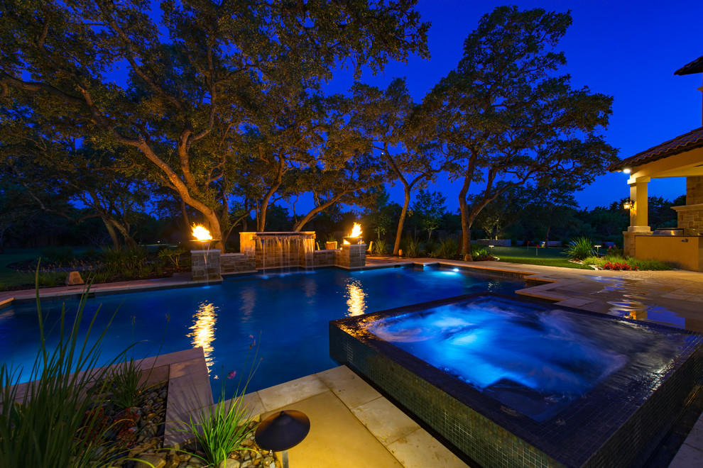 Large mediterranean backyard custom-shaped pool in Austin with a hot tub and concrete pavers.
