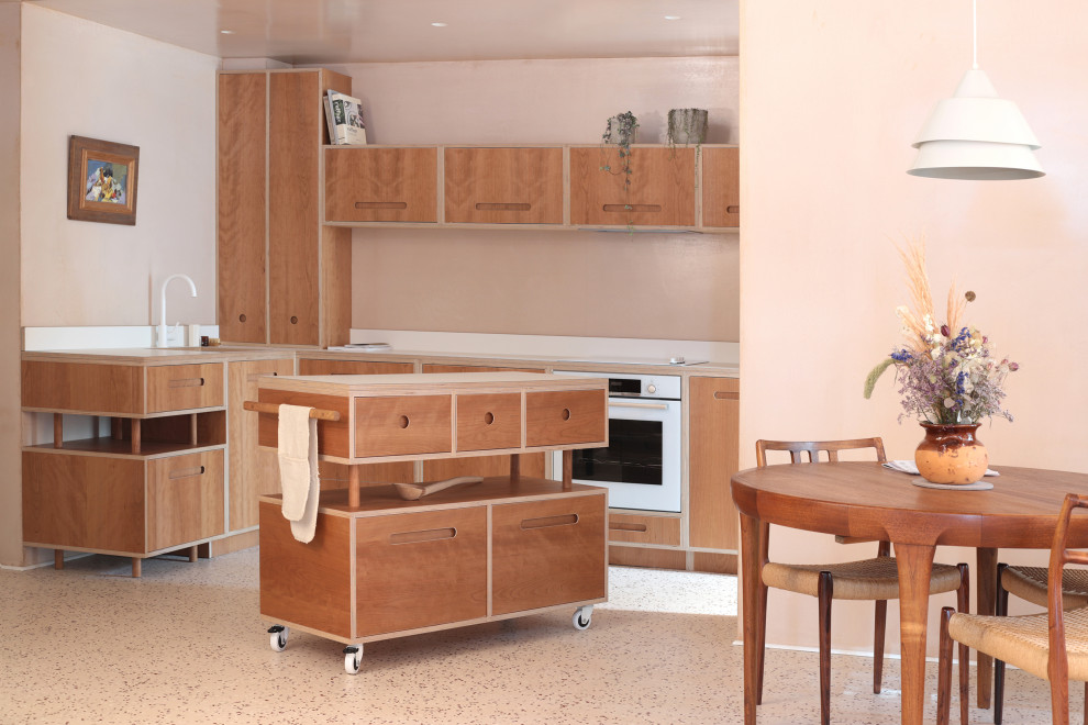 This is an example of a mid-sized contemporary l-shaped open plan kitchen in London with an undermount sink, flat-panel cabinets, medium wood cabinets, laminate benchtops, beige splashback, panelled appliances, with island, beige floor and white benchtop.