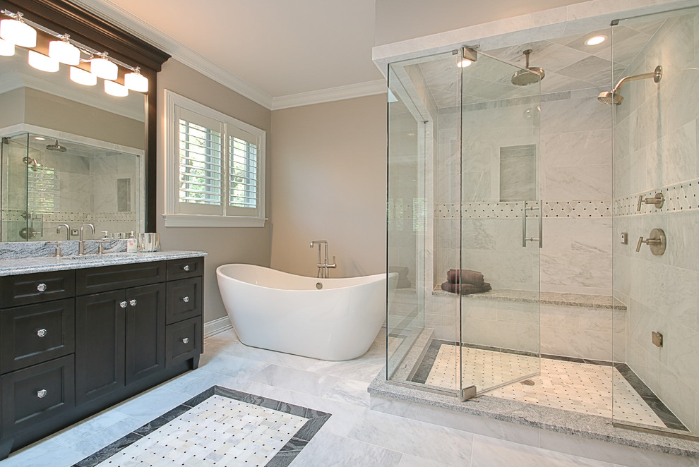 Inspiration for a traditional bathroom in Chicago with recessed-panel cabinets, dark wood cabinets, a freestanding tub, a corner shower, gray tile, stone tile, brown walls, marble floors, an undermount sink, quartzite benchtops, grey floor and a hinged shower door.