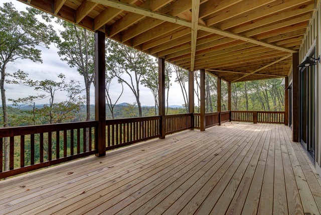 Mid-sized mountain style backyard deck photo with a fire pit and a roof extension