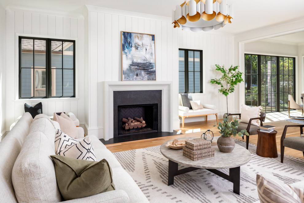 Klassisches Wohnzimmer mit weißer Wandfarbe, hellem Holzboden, Kamin, Kaminumrandung aus Stein, braunem Boden und Holzdielenwänden in Charlotte