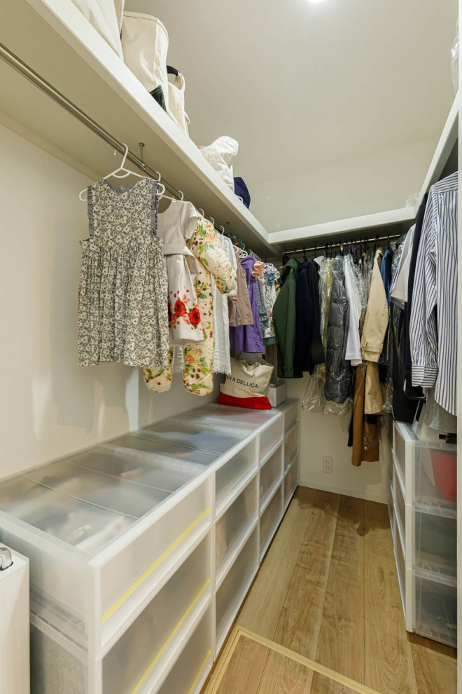 Photo of a mid-sized industrial gender-neutral storage and wardrobe in Tokyo Suburbs with light hardwood floors, beige floor and wallpaper.
