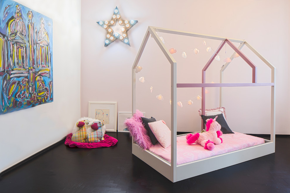 Design ideas for a modern kids' playroom for kids 4-10 years old and girls in Rome with pink walls, painted wood floors and black floor.