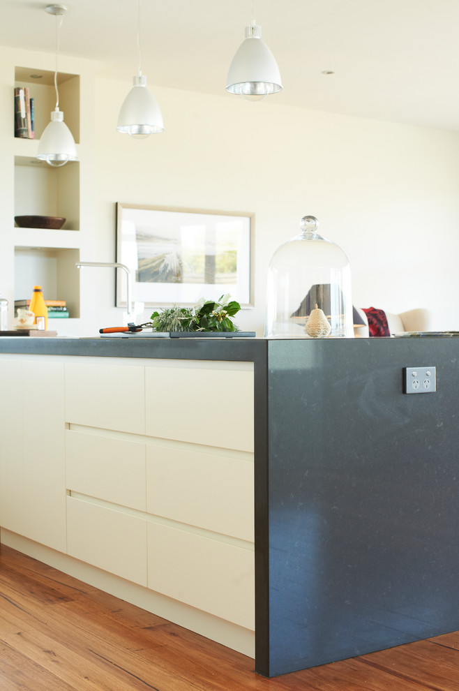 Photo of a mid-sized contemporary u-shaped eat-in kitchen in Melbourne with a double-bowl sink, flat-panel cabinets, white cabinets, granite benchtops, white splashback, ceramic splashback, stainless steel appliances and light hardwood floors.