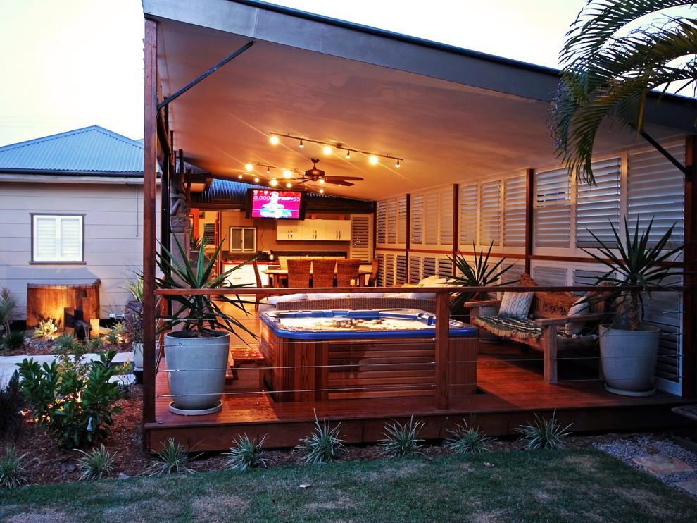 Design ideas for a large tropical backyard deck in Dallas with a roof extension and an outdoor kitchen.