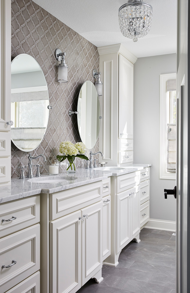 Mid-sized traditional master bathroom in Minneapolis with beaded inset cabinets, white cabinets, a corner shower, gray tile, ceramic tile, grey walls, porcelain floors, an undermount sink, marble benchtops, grey floor, a hinged shower door and white benchtops.