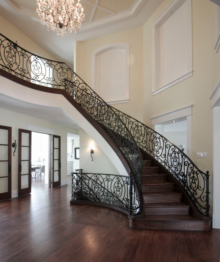 Design ideas for an expansive transitional wood curved staircase in DC Metro with wood risers and metal railing.