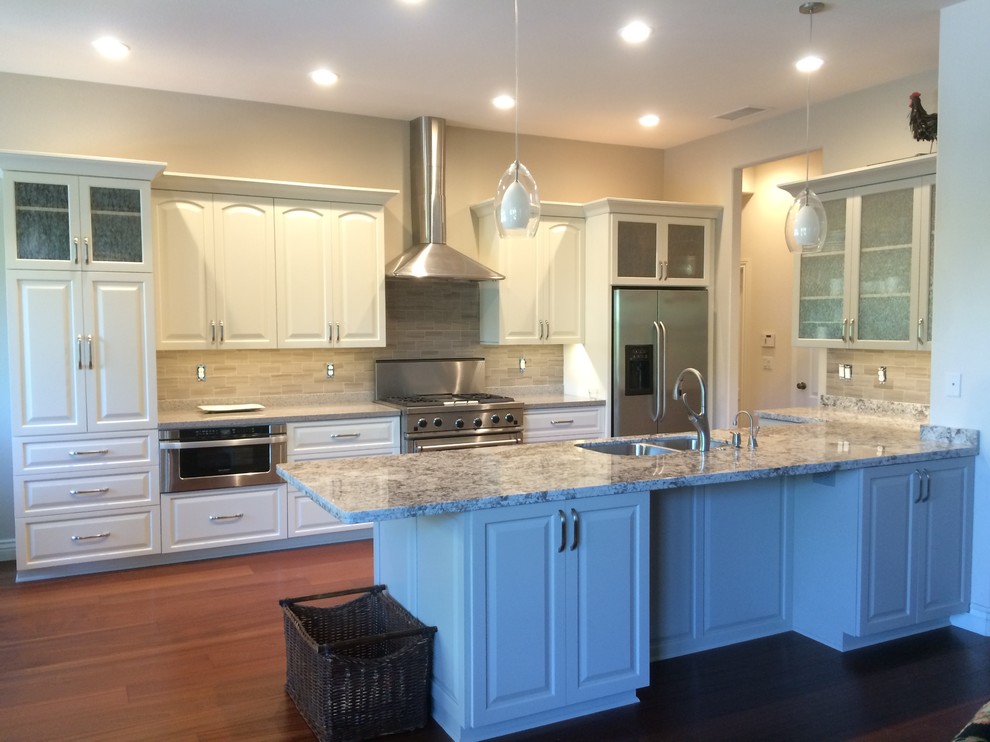 Design ideas for a large traditional u-shaped eat-in kitchen in Sacramento with an undermount sink, raised-panel cabinets, white cabinets, granite benchtops, grey splashback, porcelain splashback, stainless steel appliances, medium hardwood floors, with island and brown floor.