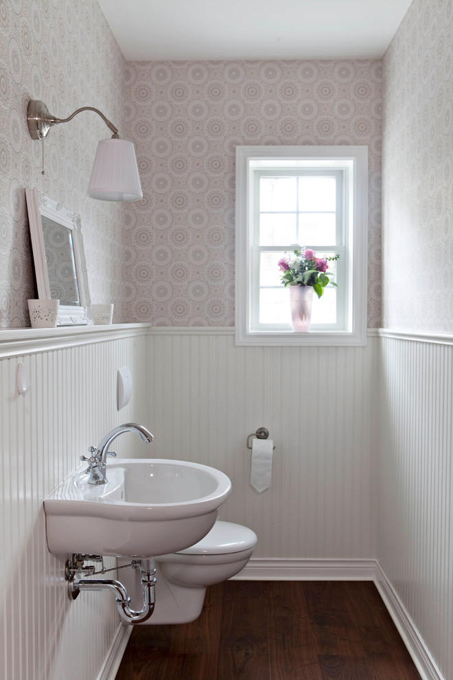 Photo of a country powder room in Berlin with a wall-mount sink, dark hardwood floors, a wall-mount toilet and multi-coloured walls.