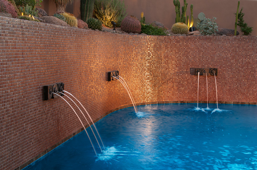 This is an example of a large contemporary backyard custom-shaped infinity pool in Phoenix with a water feature and tile.