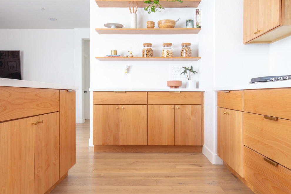 Inspiration for a mid-sized midcentury u-shaped eat-in kitchen in Phoenix with an undermount sink, flat-panel cabinets, light wood cabinets, quartz benchtops, white splashback, stainless steel appliances, light hardwood floors, with island, brown floor and white benchtop.