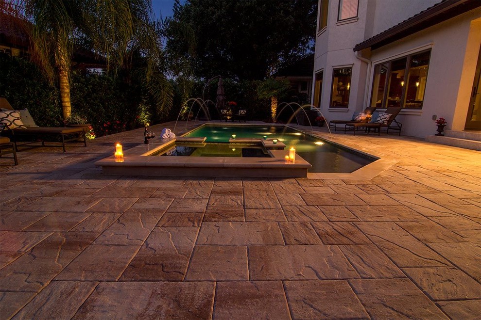 Inspiration for a mid-sized mediterranean backyard custom-shaped pool with a water feature and concrete pavers.