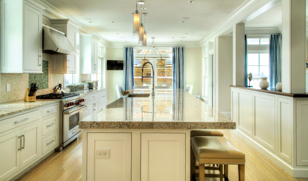 Inspiration for a large transitional single-wall light wood floor and beige floor open concept kitchen remodel in Providence with a farmhouse sink, beaded inset cabinets, white cabinets, granite countertops, beige backsplash, mosaic tile backsplash, stainless steel appliances and an island