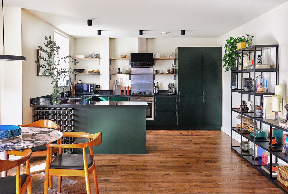 Mid-sized eclectic u-shaped open plan kitchen in London with a single-bowl sink, flat-panel cabinets, green cabinets, marble benchtops, stainless steel appliances, dark hardwood floors, no island, brown floor and black benchtop.