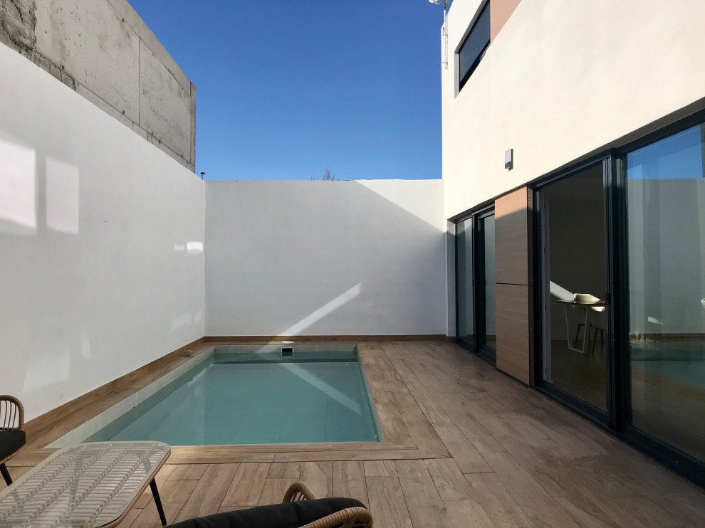 Modelo de piscina alargada minimalista de tamaño medio rectangular en patio lateral con privacidad y suelo de baldosas