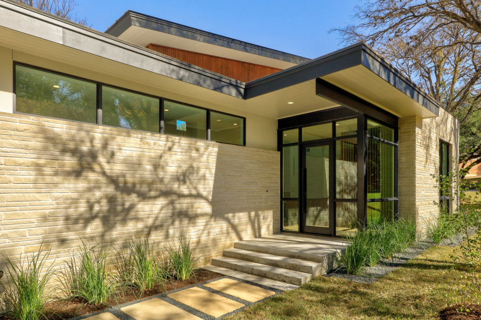 Example of a mid-sized mid-century modern white one-story stone exterior home design in Austin with a metal roof and a black roof