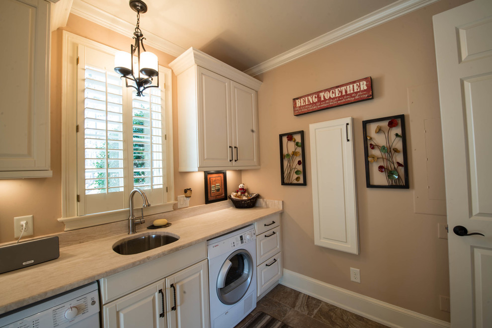 Photo of a mid-sized traditional galley utility room in Atlanta with white cabinets, a side-by-side washer and dryer, an undermount sink, raised-panel cabinets, limestone benchtops, beige walls and porcelain floors.