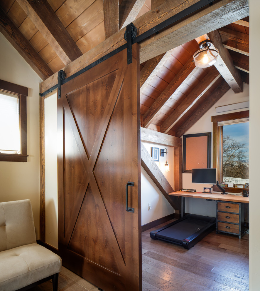 This is an example of a medium sized rustic study in Denver with medium hardwood flooring, a built-in desk and exposed beams.