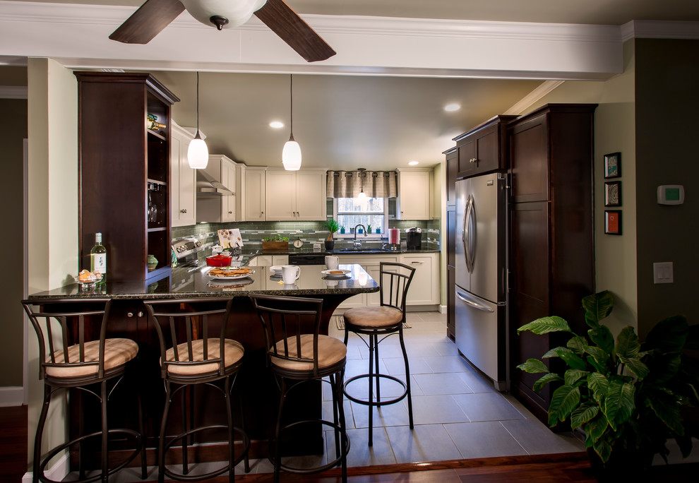Open concept kitchen - large traditional u-shaped ceramic tile open concept kitchen idea in Charlotte with a drop-in sink, shaker cabinets, white cabinets, solid surface countertops, green backsplash, matchstick tile backsplash, stainless steel appliances and no island