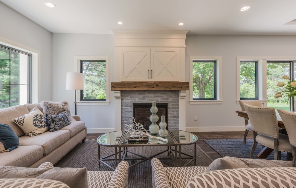 Mid-sized country formal open concept living room in Minneapolis with medium hardwood floors, a standard fireplace, brown floor, a concealed tv, grey walls and a tile fireplace surround.