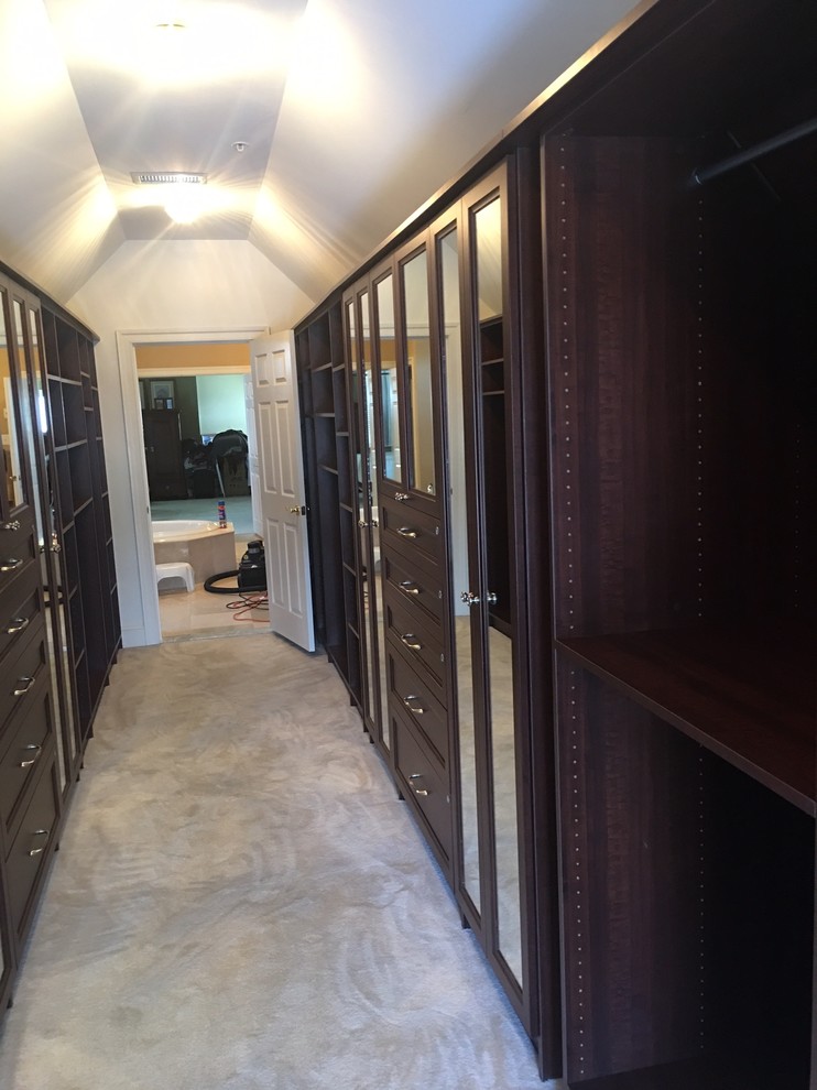 Design ideas for a large transitional gender-neutral walk-in wardrobe in Philadelphia with recessed-panel cabinets, dark wood cabinets and carpet.