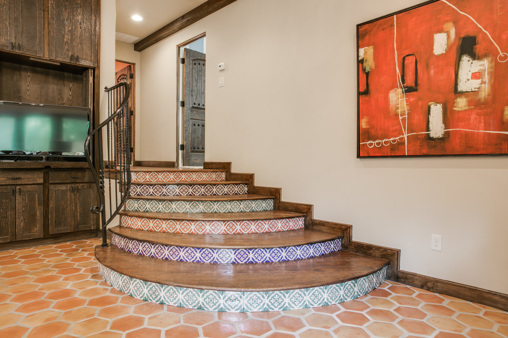 Large mediterranean wood curved staircase in Dallas with tile risers and metal railing.