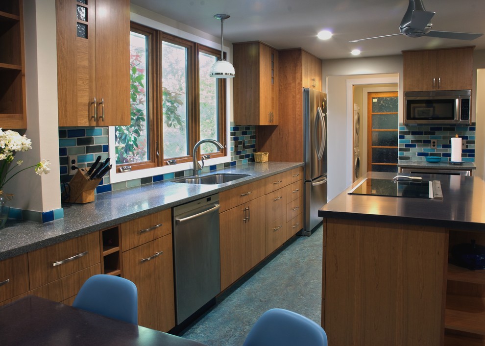 This is an example of a traditional galley kitchen in DC Metro with stainless steel appliances, concrete benchtops, flat-panel cabinets, medium wood cabinets, multi-coloured splashback, subway tile splashback and blue floor.