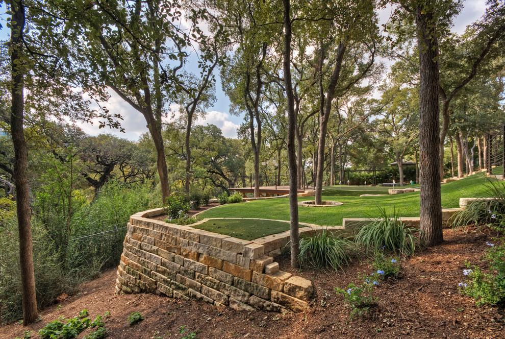 Inspiration for a large traditional front yard shaded xeriscape for spring in Austin with a retaining wall and natural stone pavers.