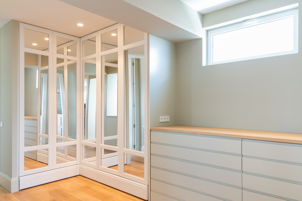Modelo de vestidor unisex clásico renovado de tamaño medio con puertas de armario de madera clara, suelo de madera en tonos medios y suelo marrón