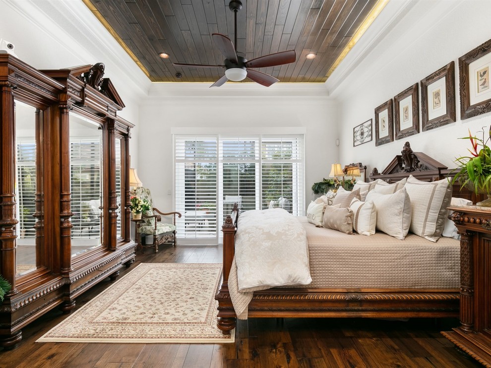 Mediterranean master bedroom in Orlando with white walls, dark hardwood floors, no fireplace and brown floor.