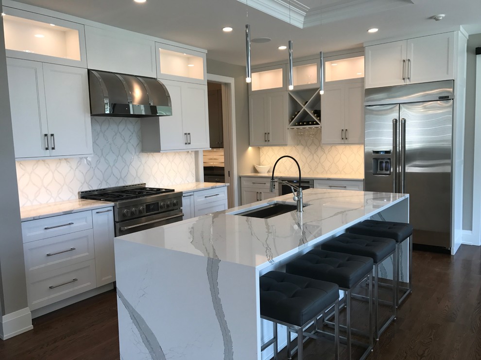 Photo of a large modern l-shaped eat-in kitchen in New York with shaker cabinets, white cabinets, with island, an undermount sink, quartzite benchtops, white splashback, stainless steel appliances, dark hardwood floors and brown floor.