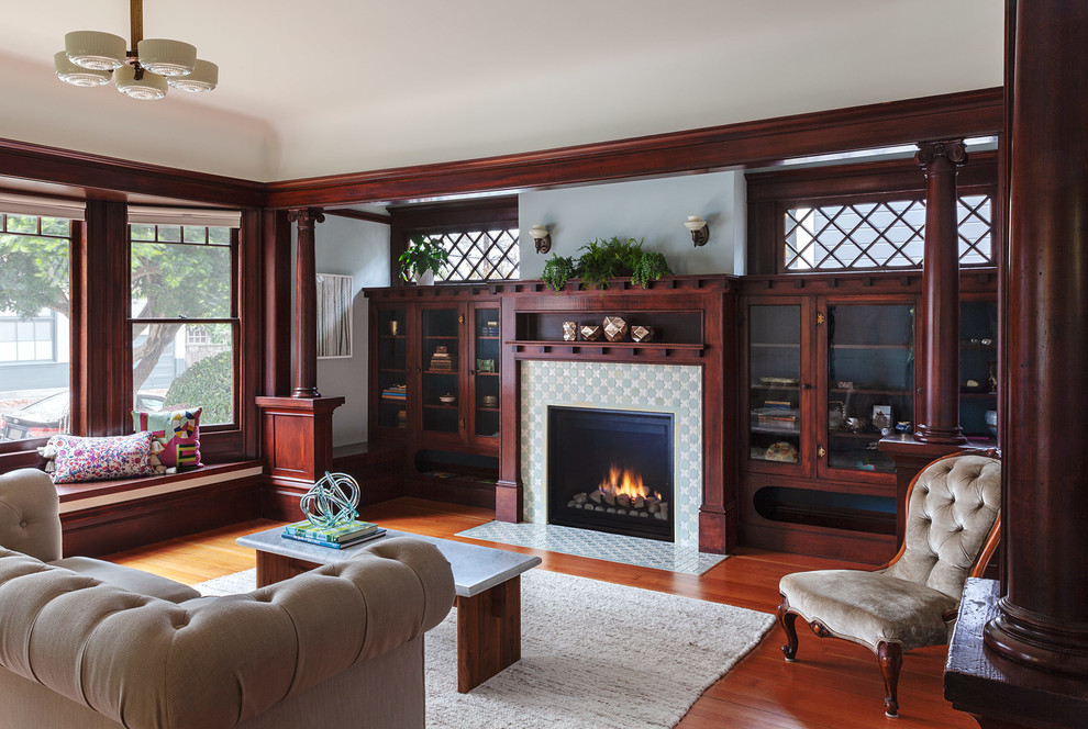 Inspiration for a traditional family room in San Francisco with a library, blue walls, medium hardwood floors, a standard fireplace and a tile fireplace surround.