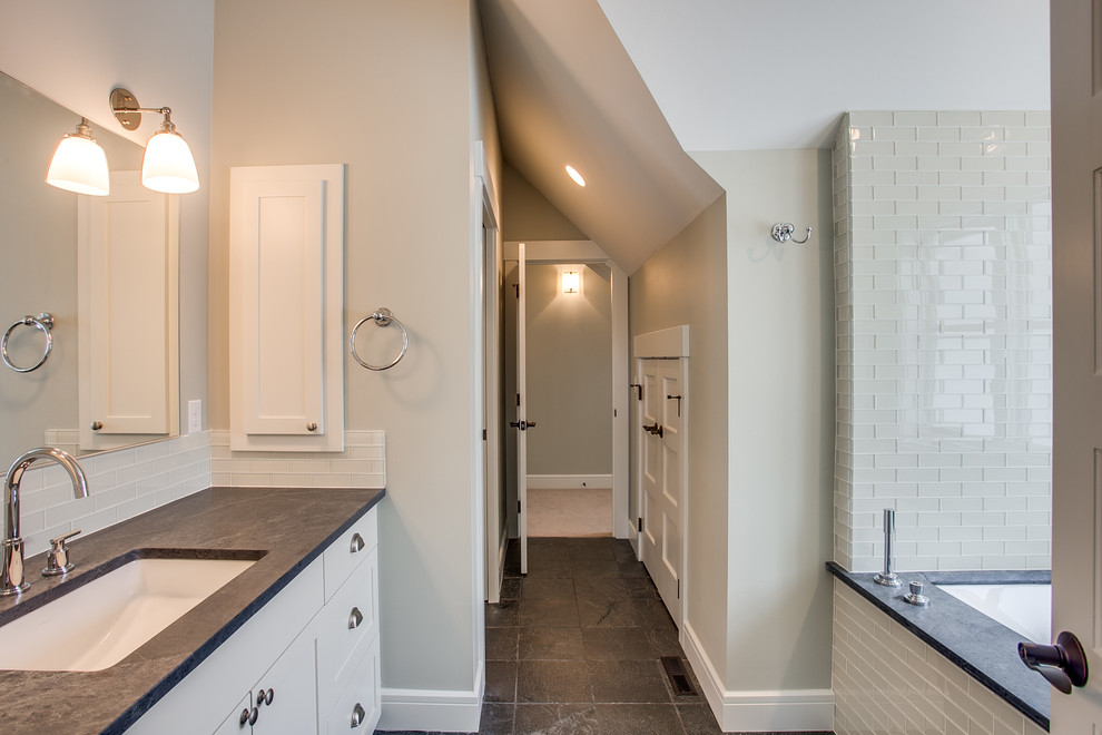 This is an example of a small country bathroom in Seattle with shaker cabinets, white cabinets, an undermount tub, a shower/bathtub combo, white tile, glass tile, slate floors, an undermount sink and soapstone benchtops.