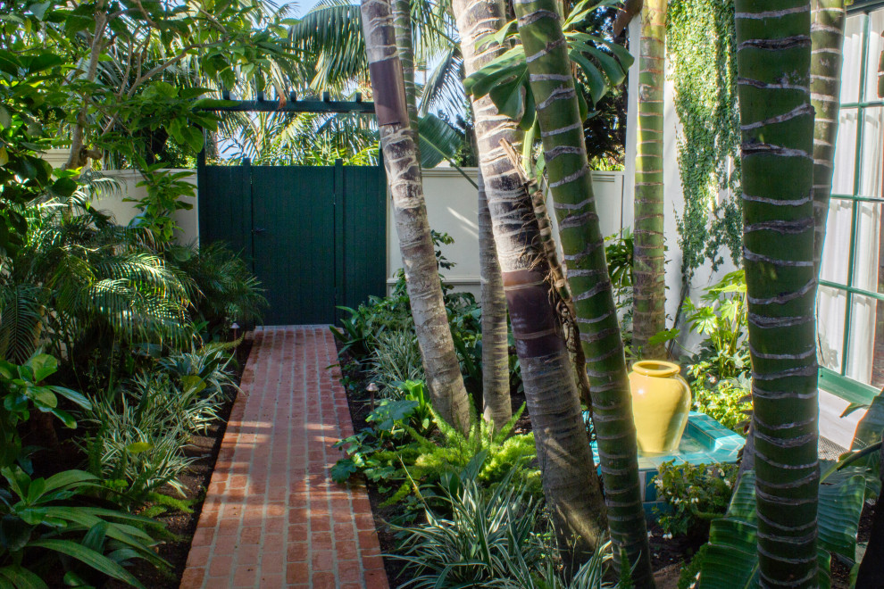 This is an example of a small tropical side yard partial sun garden for summer in Santa Barbara with a garden path and brick pavers.