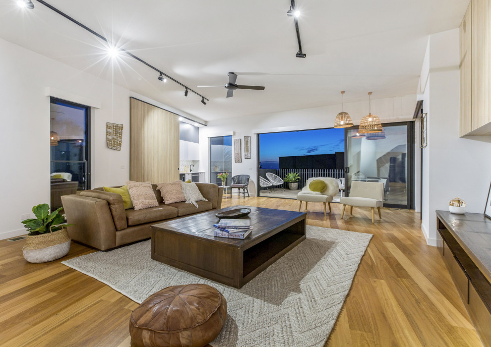 Geräumiges, Offenes Maritimes Wohnzimmer mit weißer Wandfarbe, hellem Holzboden und gewölbter Decke in Melbourne