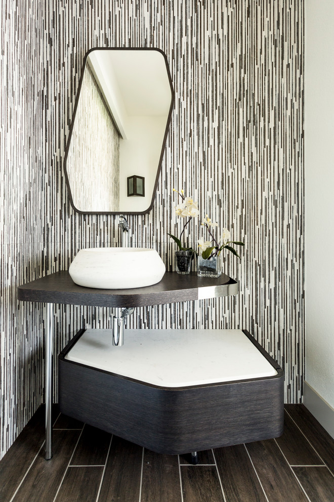 Mid-sized contemporary powder room in Denver with a vessel sink, solid surface benchtops, brown floor, dark wood cabinets and multi-coloured walls.