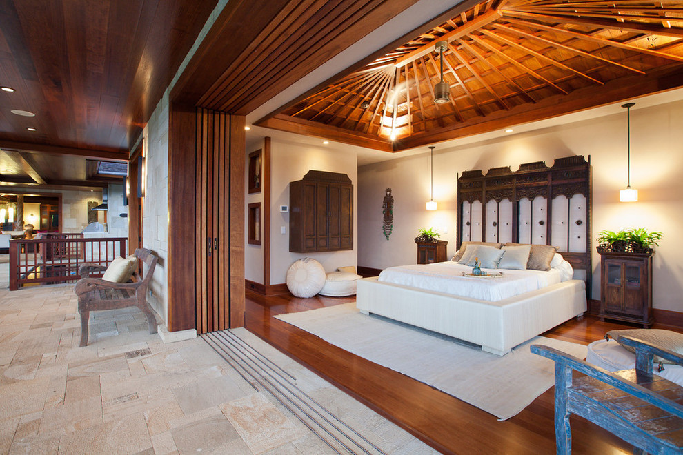 Photo of a large tropical master bedroom in Hawaii with white walls, medium hardwood floors and no fireplace.
