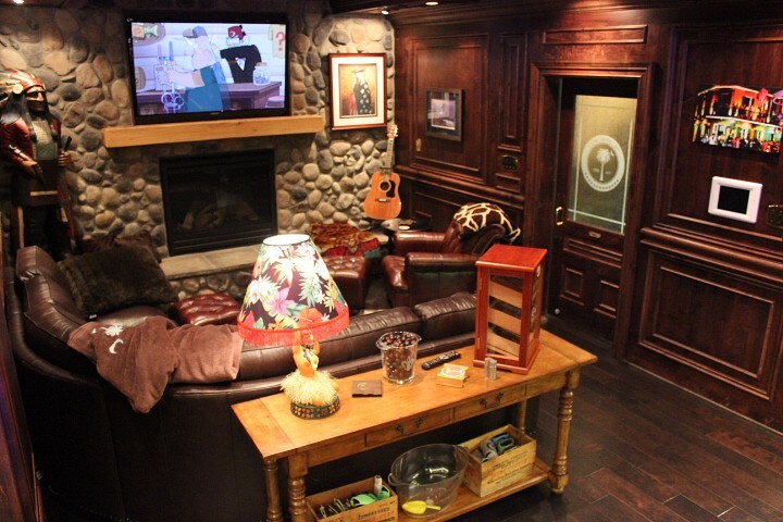 Example of a mid-sized mountain style walk-out dark wood floor and brown floor basement design with brown walls, a standard fireplace and a stone fireplace