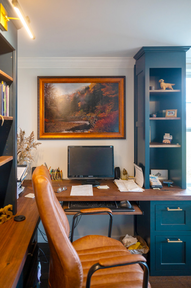 Medium sized classic study in New York with white walls, dark hardwood flooring, no fireplace, a built-in desk and brown floors.