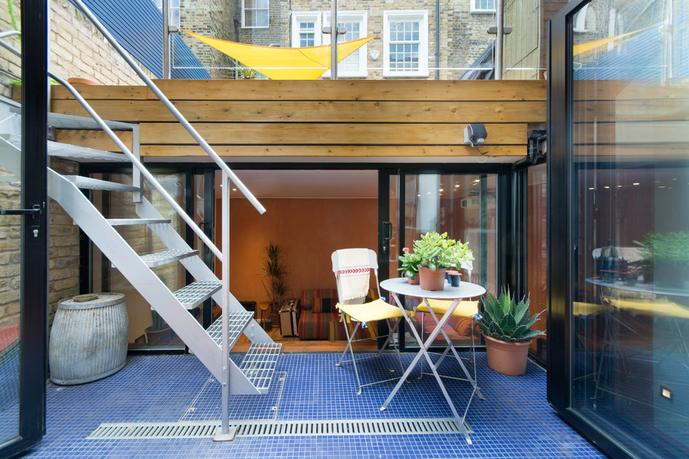 This is an example of a contemporary courtyard patio in London with a container garden, tile and no cover.