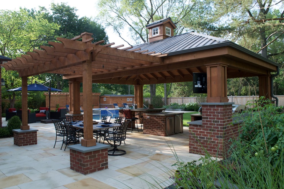 This is an example of a large contemporary backyard patio in Chicago with an outdoor kitchen, natural stone pavers and a gazebo/cabana.