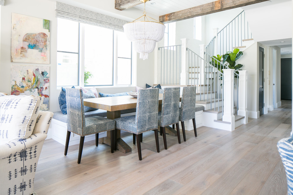 Inspiration for a beach style dining room in Orange County with white walls, medium hardwood floors and beige floor.