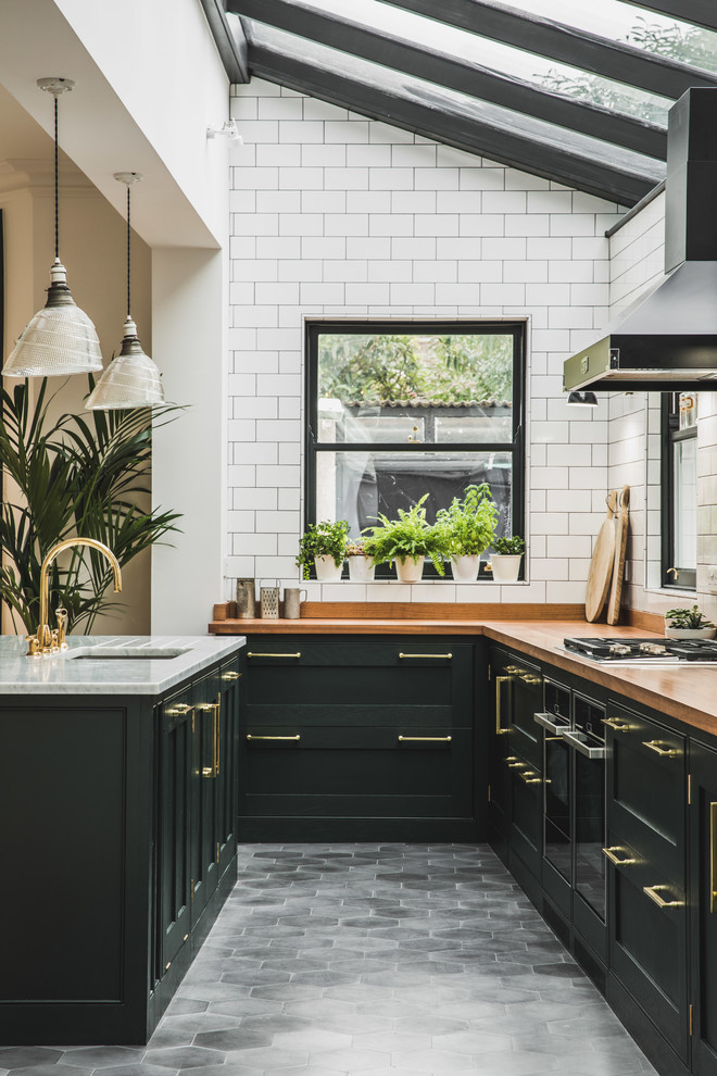 Design ideas for a traditional l-shaped open plan kitchen in London with an undermount sink, shaker cabinets, green cabinets, wood benchtops, white splashback, subway tile splashback, cement tiles, with island and grey floor.