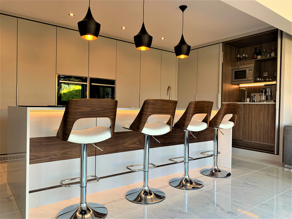 Photo of a large contemporary l-shaped open plan kitchen in Other with a drop-in sink, flat-panel cabinets, dark wood cabinets, quartz benchtops, black appliances, porcelain floors and with island.